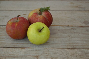 
red and one green apple on a wooden table
