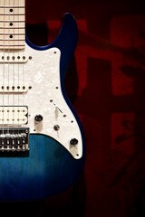Beautiful, new, blue and white electric guitar with red background. Modern minimlaistic close-up photo with space for text.