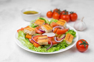 Traditional Middle Eastern vegetarian salad fattoush. Lebanese cuisine recipe. Fresh vegetables, cherry, lettuce, toasted pita bread. White concrete background. Low-calorie, healthy meal, close up. 