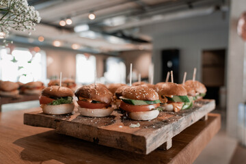 Tasty Burgers on a wooden board, beautifully prepared and well arranged. Finger food style. Dinner party invitation for lunch and lifestyle catering event served with bokeh and feeling hungry gourmet.
