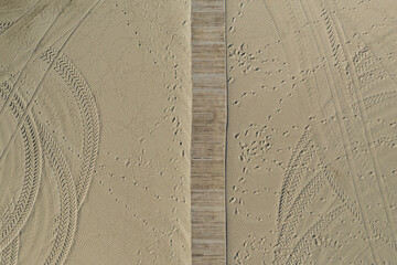 Vue aérienne en drone au dessus d'une passerelle en bois aménagée sur une plage de sable