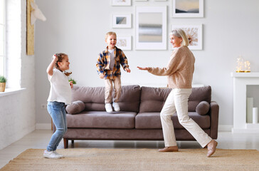 Cheerful grandmother dancing with children at home.