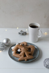 Gingerbread cookies on a white plate with a cup of tea on a white background. Christmas card. Copy space.