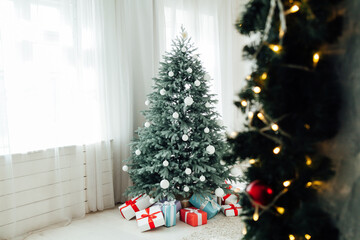 Christmas tree with presents underneath in living room. White room.