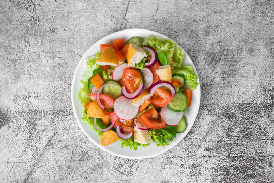 Traditional Middle Eastern vegetarian salad fattoush top view. Lebanese cuisine recipe. Fresh vegetables, cherry, lettuce, toasted pita bread. Gray concrete background. Low-calorie, healthy meal. 