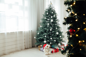 Christmas tree with presents underneath in living room. White room.