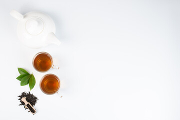 Green tea leaf and glass cup of black tea isolated on white background