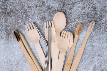 Basic set eco friendly reusable bamboo cutlery, toothbrushes, metal tubes on gray background close up. Concept of environmental protection, plastic free, zero waste. Minimalistic life