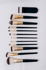 Set of makeup brushes on white fabric