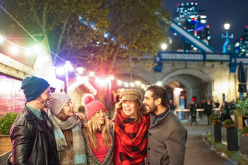 Happy Group of friends walking in London street . Young people hanging out ready for christmas night. Millennial people smiling for a joke. Christmas, new year, friendship and youth concept.Defocused 