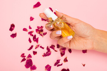 Natural herbal lotion concept. Cosmetic product bottle with rose blossom branch on a light pink background. Blank label for branding mock-up, copy space.