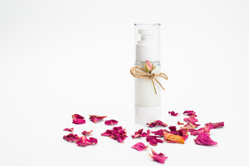 Natural herbal lotion concept. Cosmetic product bottle with rose blossom branch on a light pink background. Blank label for branding mock-up, copy space.
