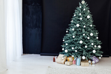 Christmas tree with presents underneath in living room. White room.