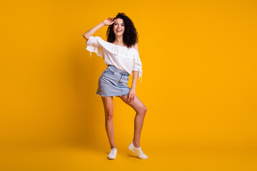 Fototapeta na wymiar Full size photo of optimistic charming brunette woman standing hand on head wear white top blue skirt sneakers isolated on yellow background