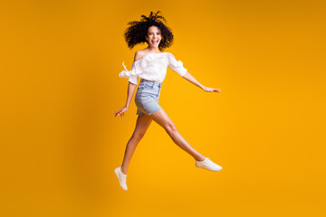 Fototapeta na wymiar Photo portrait of jumping high girl walking fast wearing jeans mini skirt throwing hair isolated on bright yellow color background