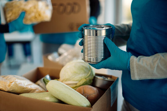 Close-up of a volunteer packing food in donation box.
