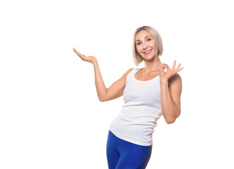 Bonus, product, sale or present from fitness club. Smiling attractive athletic caucasian adult woman in sportswear shows the OK sign and promotes any service, isolated on white.