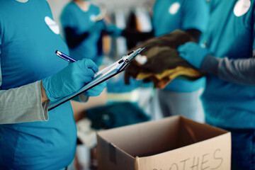 Close-up of a volunteer going through checklist while working in charitable foundation.
