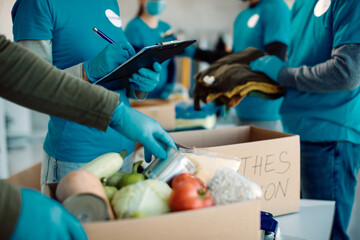 Close-up of unrecognizable volunteers packing donation boxes for charity.