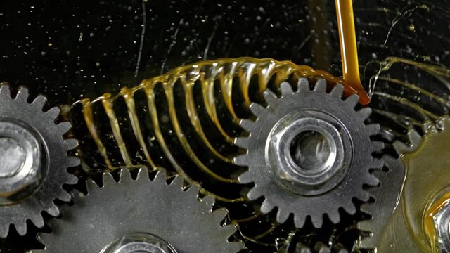 Super Slow Motion Shot of Gear Mechanism and Oil on Dark Background at 1000 fps.