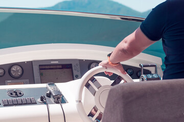 Steering wheel and dashboard of luxury yacht, hand of captain steering
