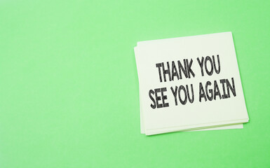 note paper written thank you and see you again over green background