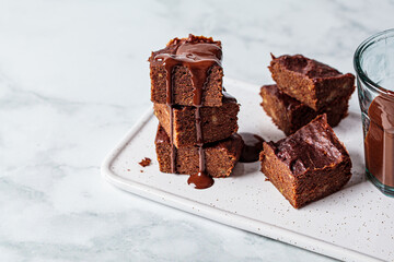 Stack of vegan brownies with dark chocolate on white board, white background, copy space. Vegan...