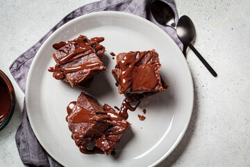 Brownie squares with dark chocolate on gray plate, gray background. Vegan dessert concept.