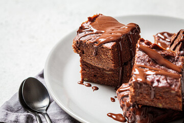 Brownie squares with dark chocolate on gray plate, gray background. Vegan dessert concept.
