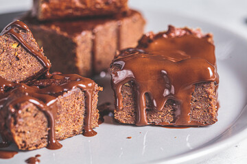 Vegan brownie squares with dark chocolate on gray plate, close-up. Vegan dessert concept.