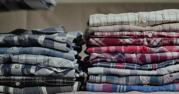Women's hands put men's shirts in a neat pile