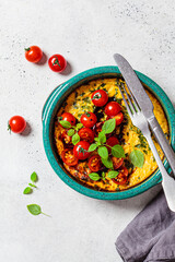 Baked omelet with tomatoes and basil in blue dish, top view. Breakfast concept.