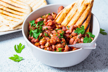 Stewed beans in tomato sauce with herbs and grilled tortillas. Vegetarian food concept.