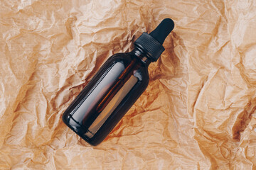 CBD oil bottle, hyaluronic acid tincture on creased cardboard. Serum with collagen and peptides on...
