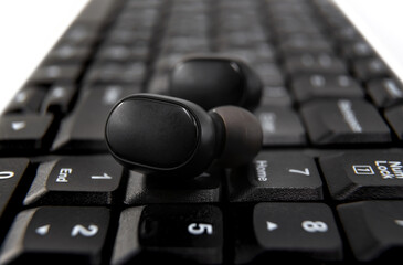 Black wireless headphones are placed on the keyboard