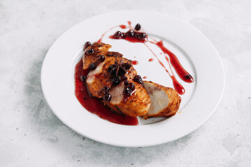 Baked chicken fillet with lingonberry sauce on a white plate, restaurant dish