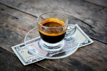 Espresso coffee shot with dollar cash on an old wooden table.