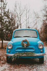 Obraz na płótnie Canvas retro car decorated with festive Christmas tree branches, gift boxes craft wrapping paper wreath pine fir needles.