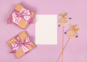 Gift boxes, christmas decorations and blank sheet of paper on pink background
