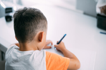 a boy is learning to write the letter K in a notebook preparing for school