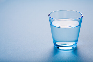 A blue clean glass of water on blue background.
