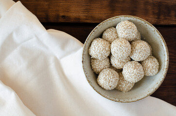 sesame seed balls made of sesame flour in bowl on linen and wooden background. Sesame sweets. Top view.