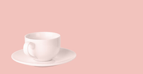 White coffee cup on saucer on a pale pink background.