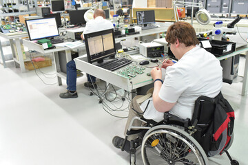handicapped worker in a wheelchair at a workplace in a electronics manufacturing and assembly...