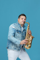 handsome musician playing the saxophone in the studio blue background. Music concept.