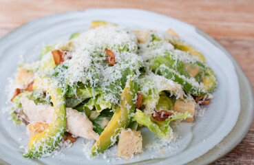 Avocado salad with vegetables, chicken and bacon in a white vintage plate. Close up view of mixed vegetable, avocado salad with bread crumb, grilled chicken and bacon. 