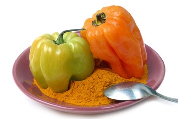 Piments antillais dans une soucoupe de curry en poudre en gros plan sur fond blanc