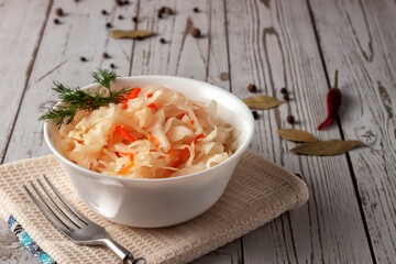 Sauerkraut with carrots and spices in a bowl. Horizontal top view, rustic style