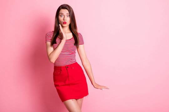 Photo of shocked charming young woman stand copyspace wear red striped t-shirt pouted lips isolated on pink color background