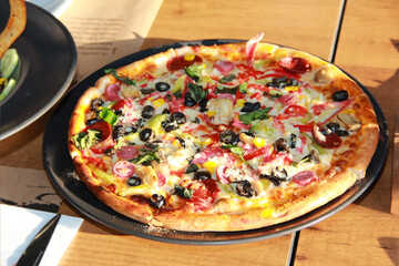 baked pizza with sausage, vegetables and olives
